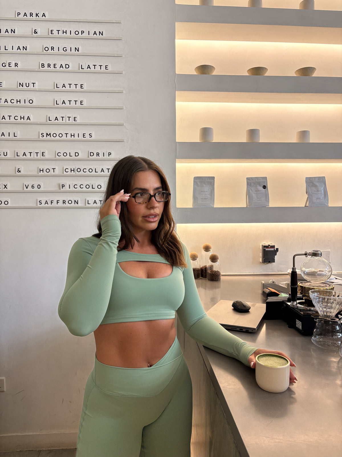 Cleo Long Sleeve Pullover in Matcha, front view at a café.
